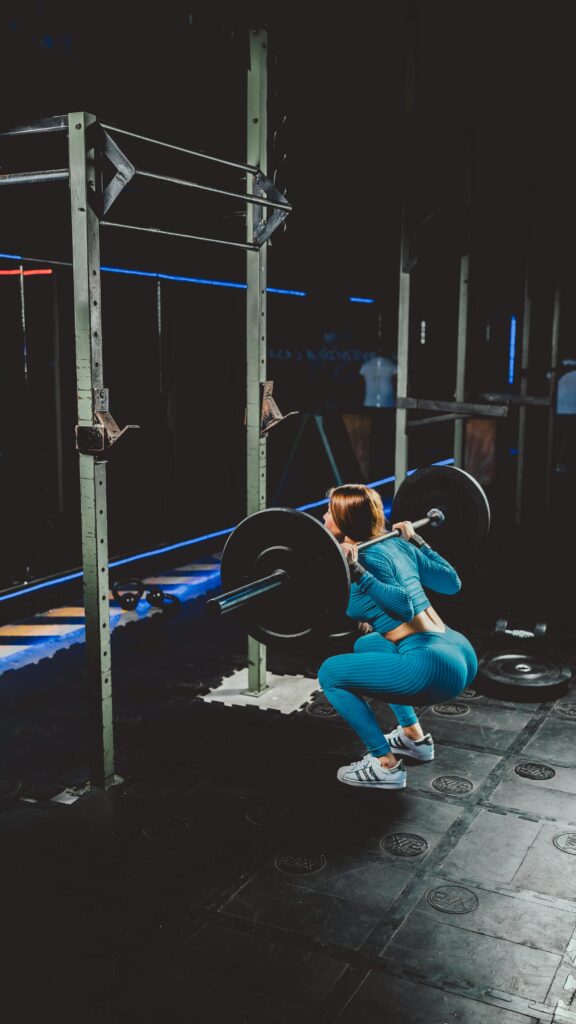 Woman squatting with a barbell in a gym, showcasing strength and fitness focus.