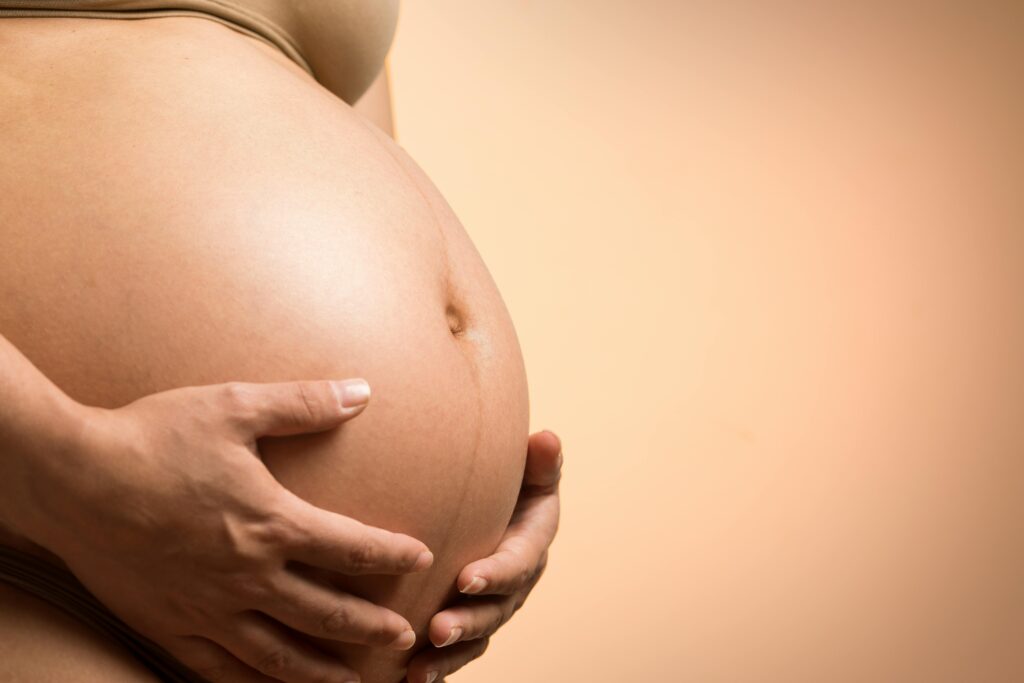 A tender close-up of a pregnant woman's hands holding her belly, symbolizing maternity and love.