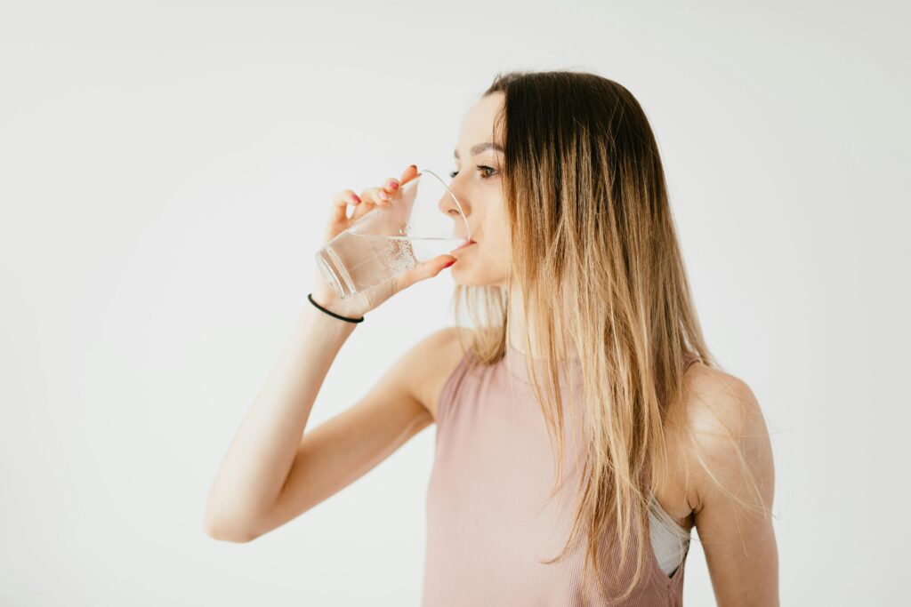 pexels-photo-4498234-4498234 Young thirsty fit female with long hair in sportswear drinking water while recreating after workout