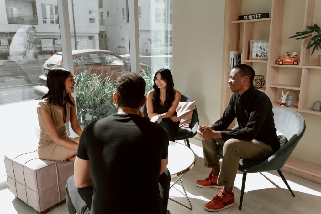 A diverse group of friends engaging in a casual conversation inside a modern coffee shop setting.