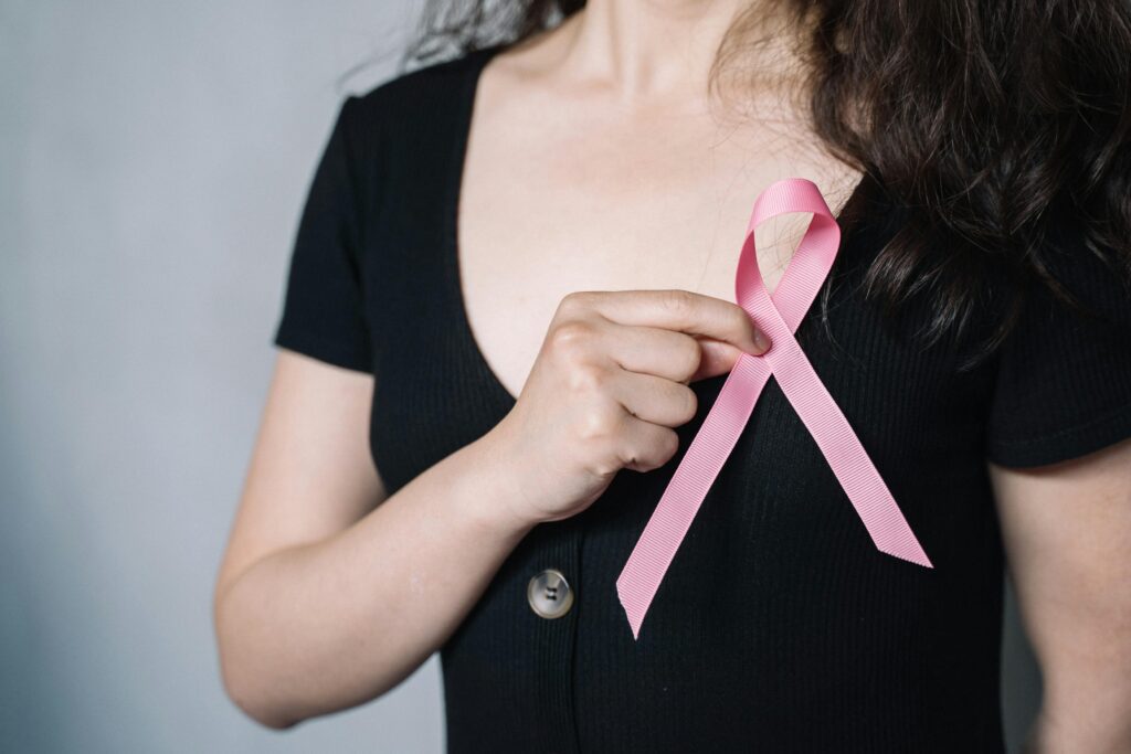 pexels-photo-5483017-5483017 Close-up of a woman holding a pink ribbon symbolizing breast cancer awareness and support.