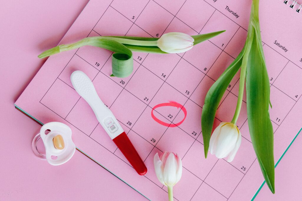 pexels-photo-5982466-5982466 Pregnancy test on pink calendar with tulips, symbolizing fertility and new beginnings.