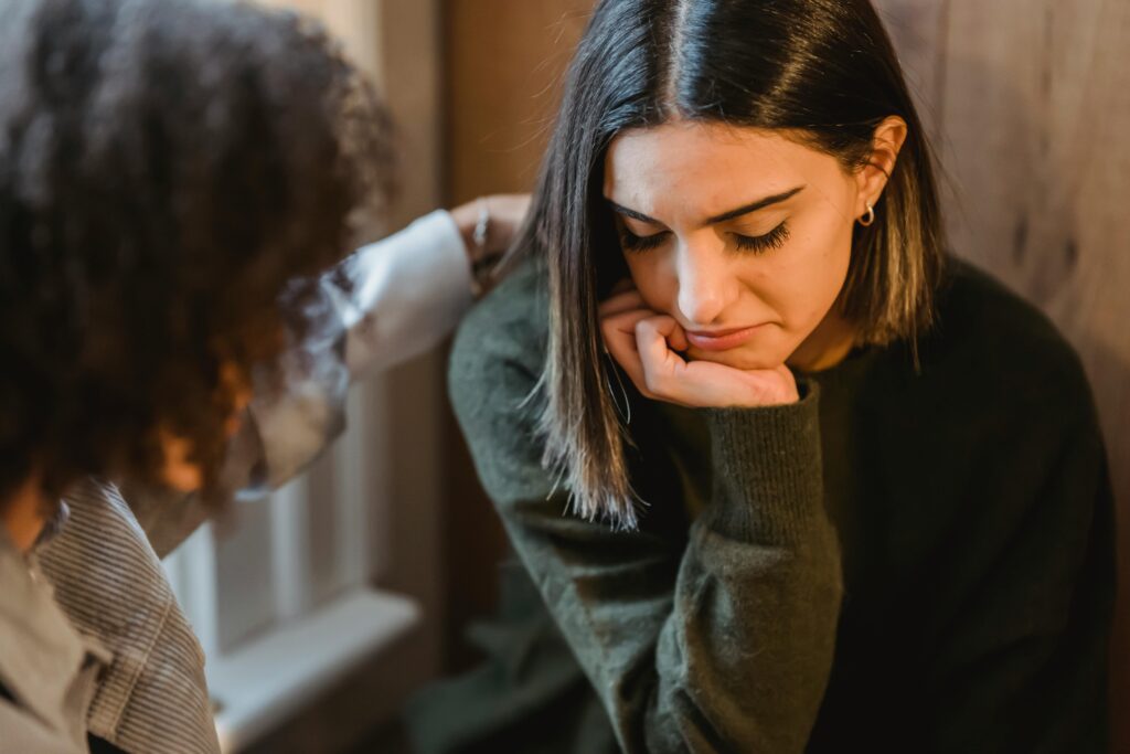 pexels-photo-6383158-6383158 Crop woman tapping shoulder and comforting upset female friend while sitting at home together