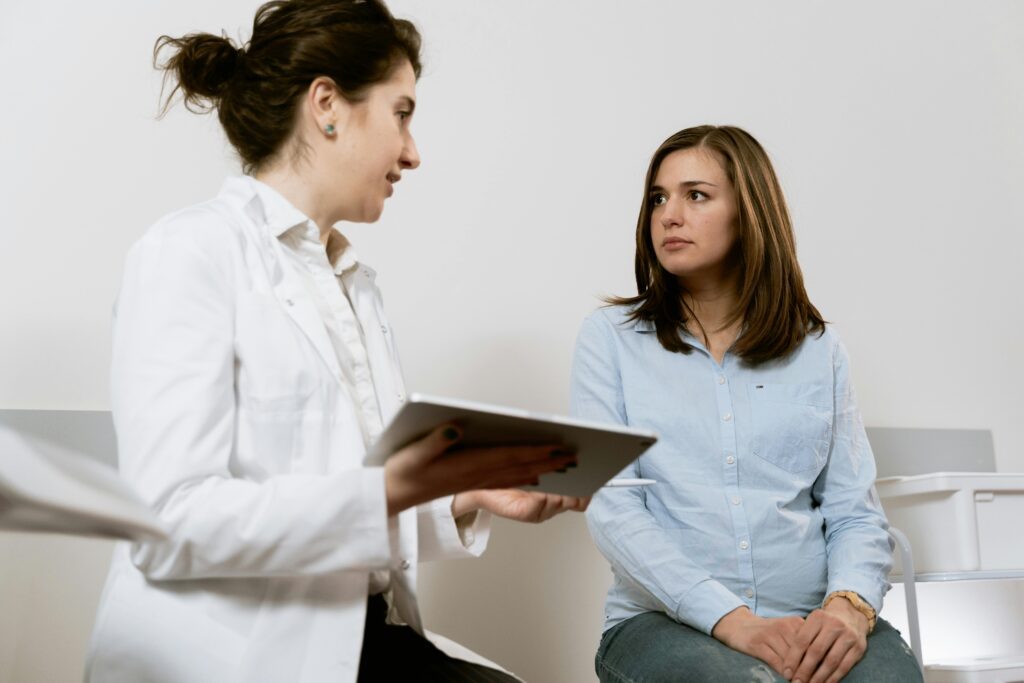 A doctor consults with a pregnant patient discussing healthcare options in a medical facility.