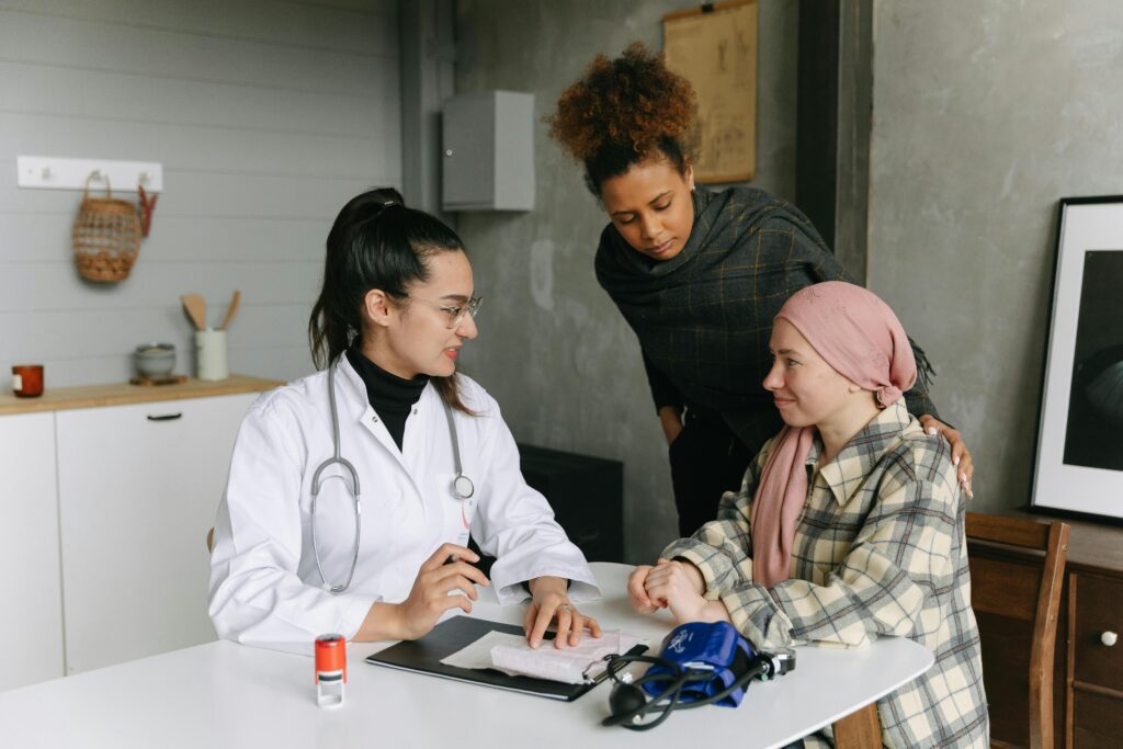 pexels-photo-7659570-7659570 A doctor consulting with cancer patient and friend at home, offering support.