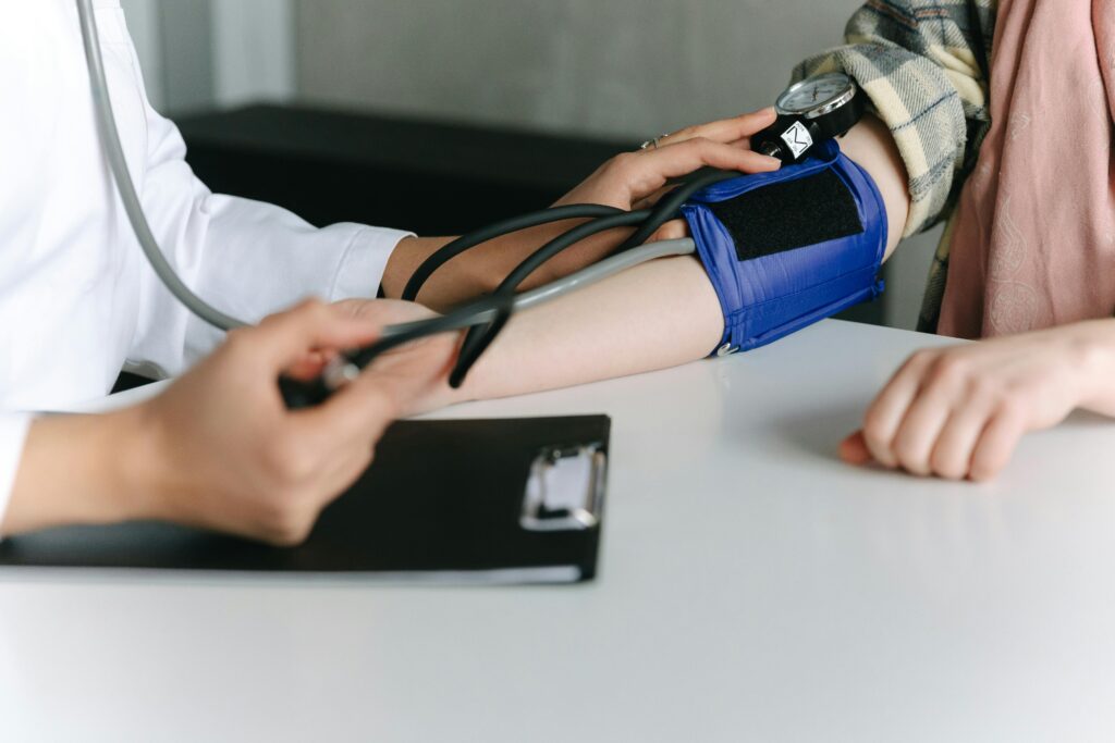 pexels-photo-7659573-7659573 A healthcare worker uses a sphygmomanometer to check a patient's blood pressure in a medical office.