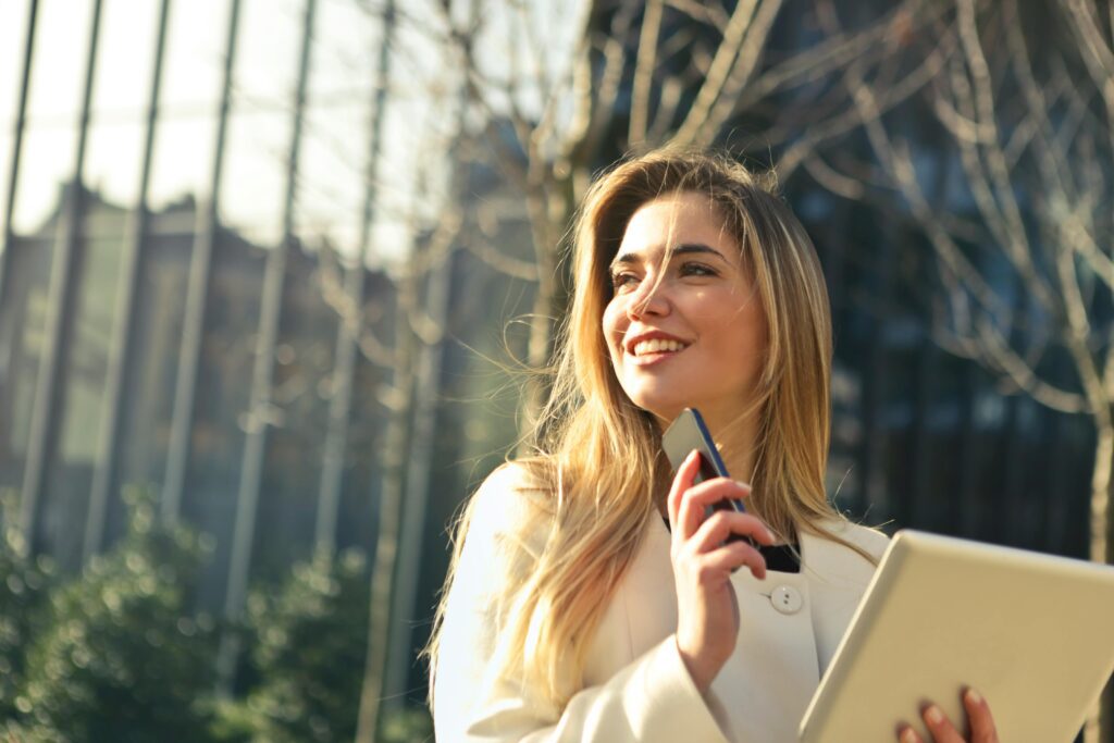 pexels-photo-864994-864994 Smiling businesswoman holding smartphone and tablet outdoors in Milan.