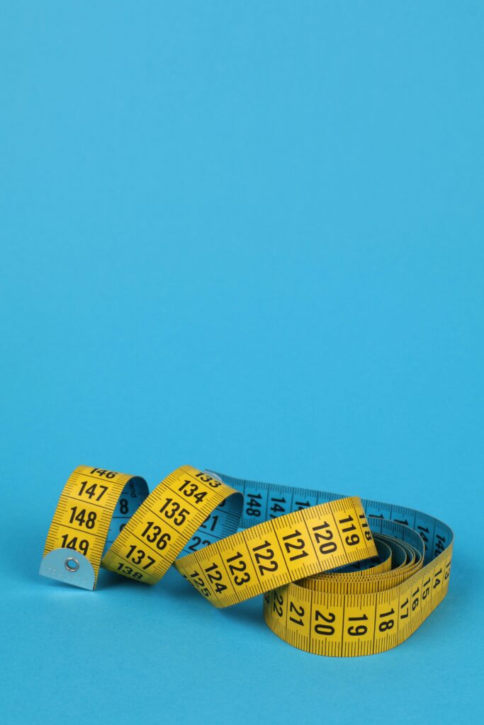 Yellow measuring tape coiled against a blue background. Perfect for design and measurement concepts.