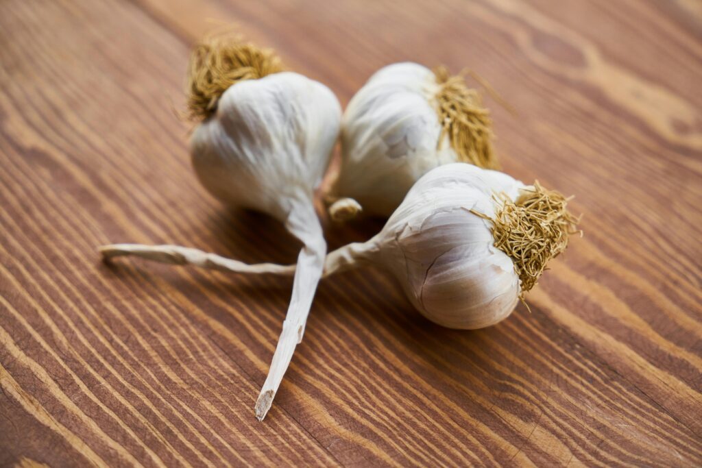 pexels-photo-1460862-1460862 Close-up of fresh garlic bulbs on a wooden surface, highlighting natural texture and freshness.