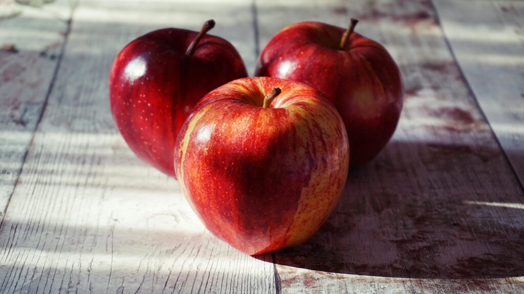 pexels-photo-1510392-1510392 Close-up of fresh red apples on a rustic wooden table captured in natural light.