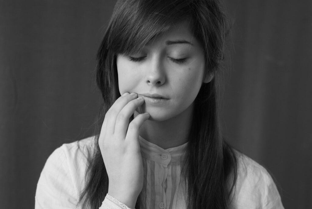 Black and white portrait of a young woman in a thoughtful pose with eyes closed.