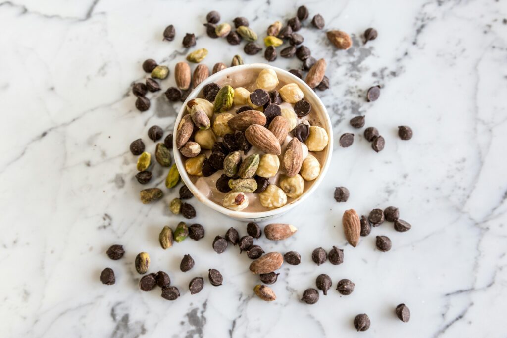 pexels-photo-2161650-2161650 A bowl of mixed nuts and chocolate chips on a marble surface, perfect for healthy snacking.