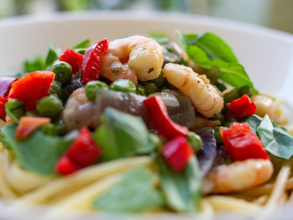 pexels-photo-2271730-2271730 Delicious shrimp pasta garnished with fresh vegetables and herbs, perfect for a healthy meal.