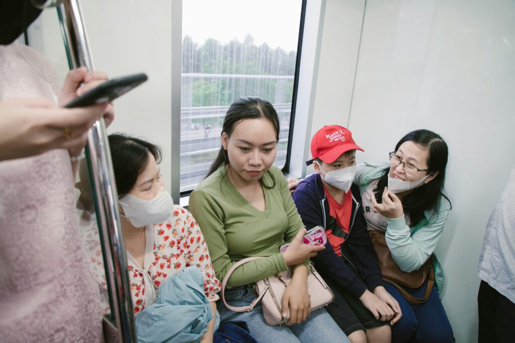 Group of people in a train wearing face masks, showing modern travel precautions.