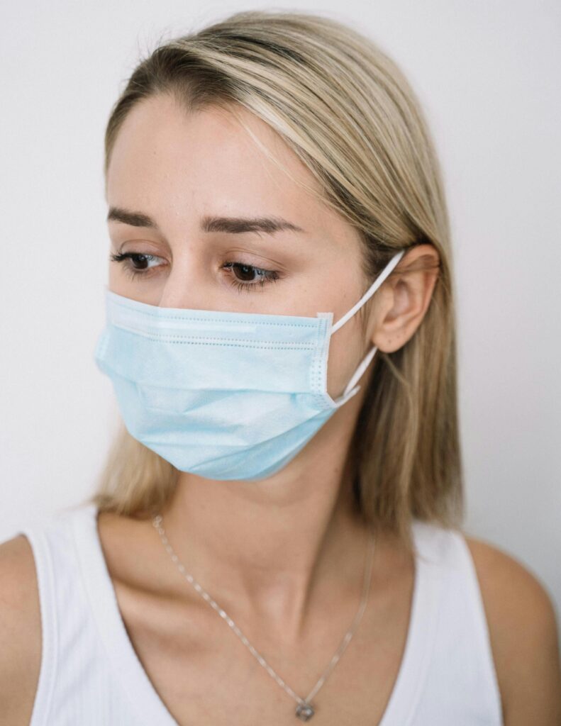 Caucasian woman with blonde hair wearing a facemask looking thoughtful.