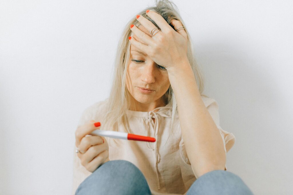 A concerned woman looks at a pregnancy test, reflecting emotions of anxiety and uncertainty.