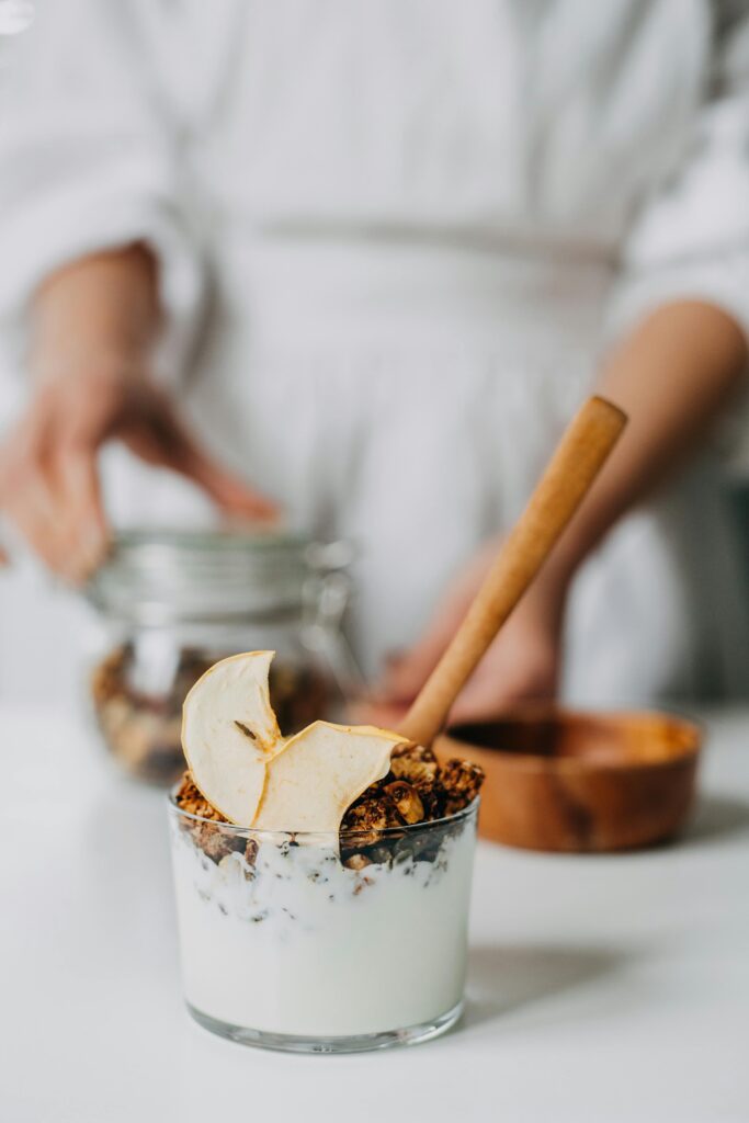 Close-up of a yogurt parfait with granola and apple slice in a glass jar, perfect for breakfast.